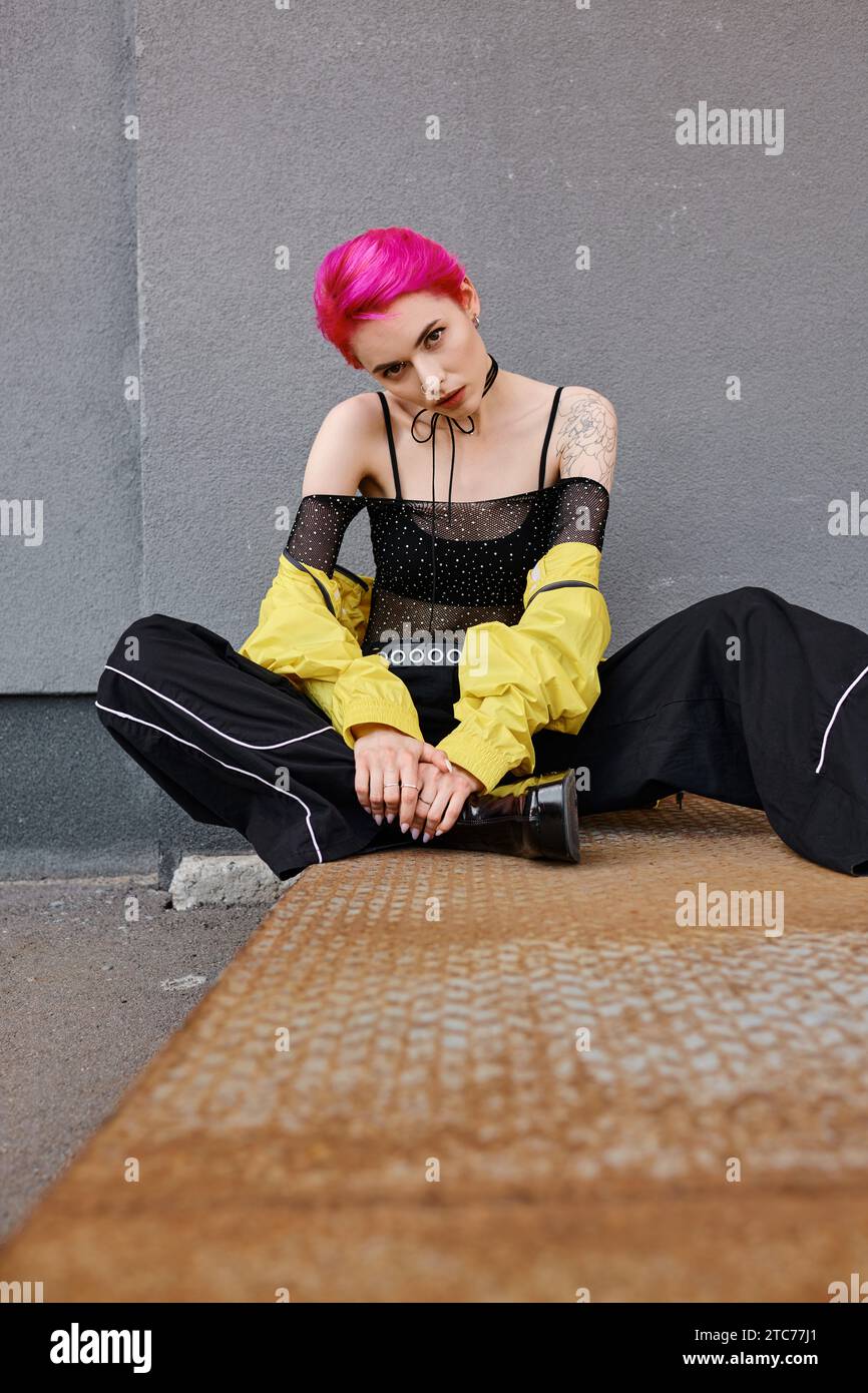 giovane donna attraente con capelli rosa corti e tatuaggi seduti a guardare la fotocamera, la moda Foto Stock