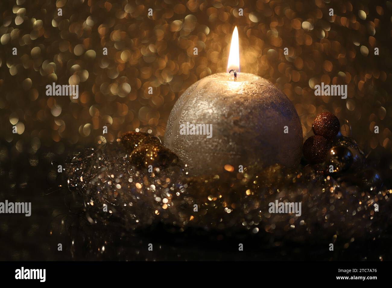 Primo piano di una candela a sfera in fiamme in un ambiente nero e oro, spazio di copia, vista laterale Foto Stock
