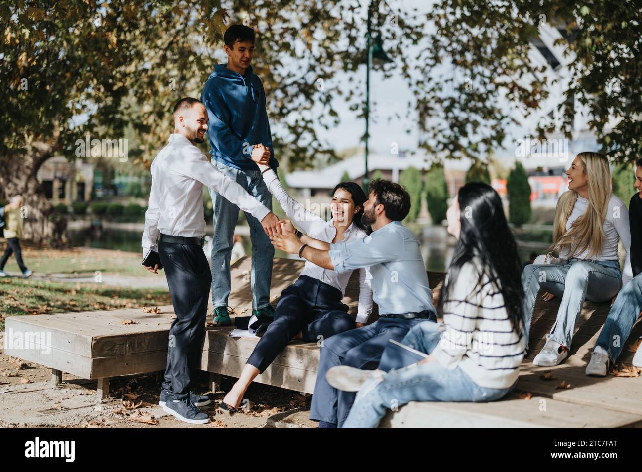Diversi studenti collaborano a un progetto universitario in un parco, favorendo un apprendimento e un lavoro di squadra efficaci. Foto Stock