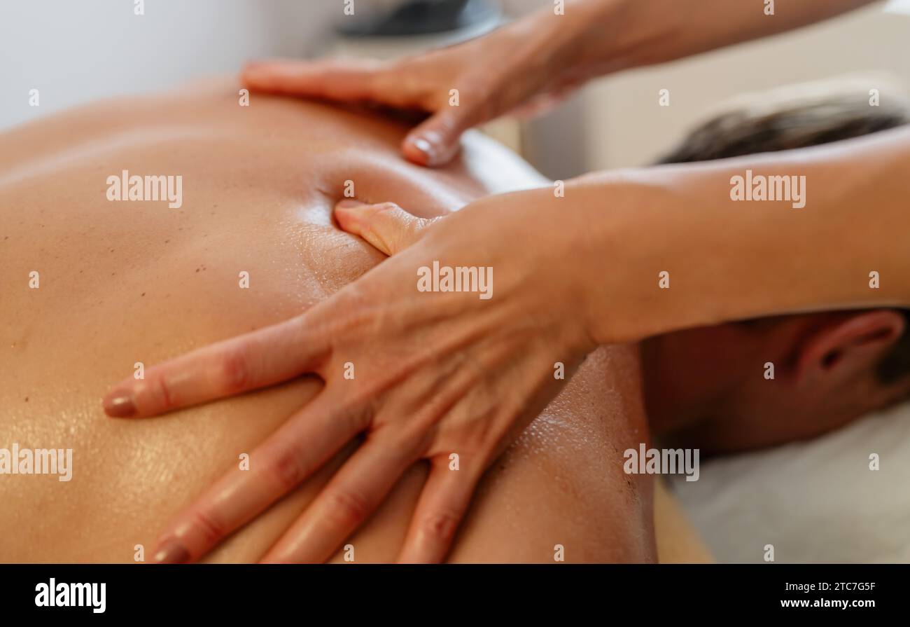 Primo piano di un terapista che fa un massaggio al collo e alle spalle a un uomo sdraiato Foto Stock