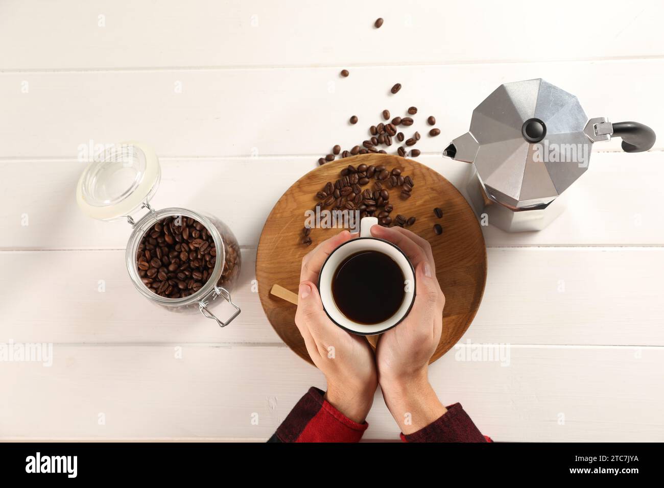Uomo con una tazza di caffè aromatico, vista dall'alto. Moka e fagioli su un tavolo di legno bianco Foto Stock