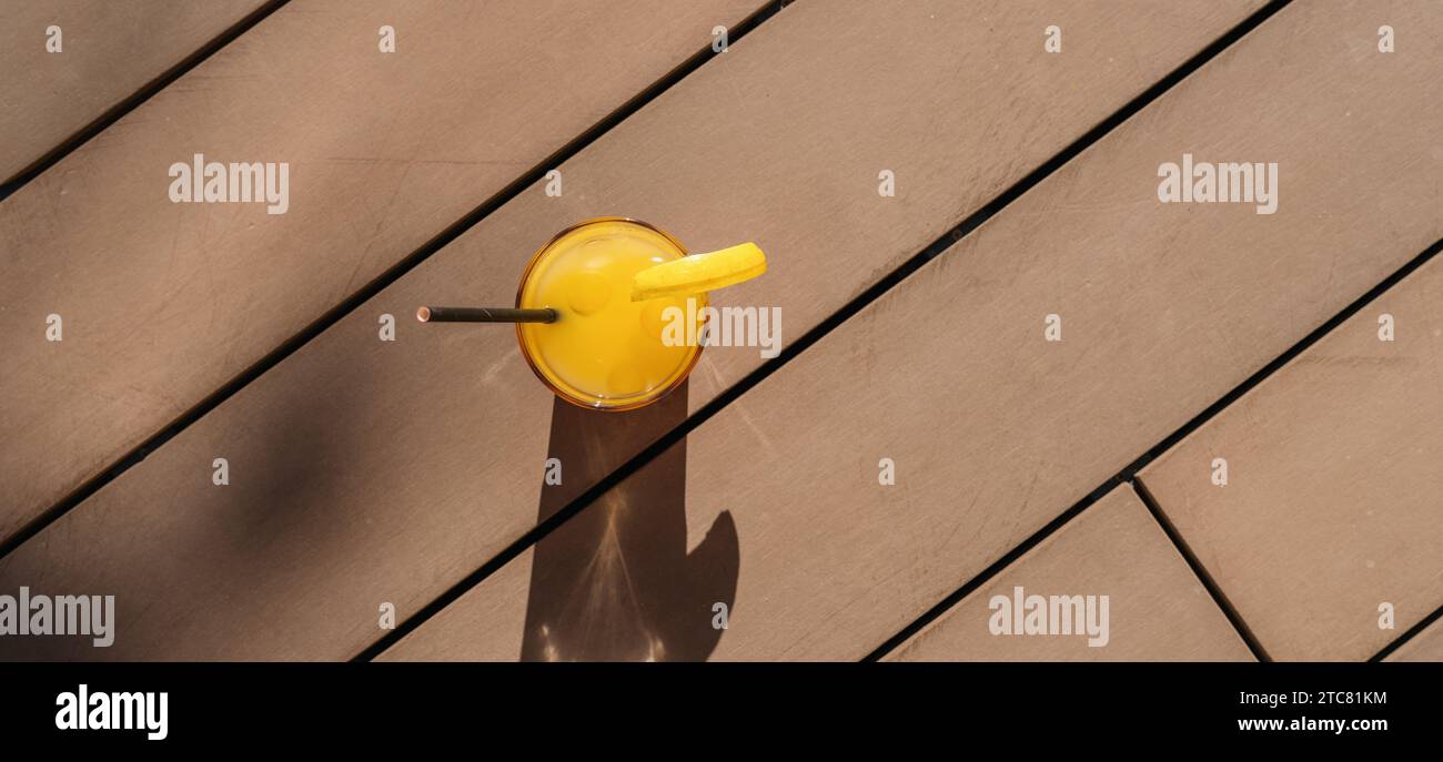 cocktail con arancio su un soleggiato ponte di legno, creando una lunga ombra in un hotel dell'isola caraibica Foto Stock
