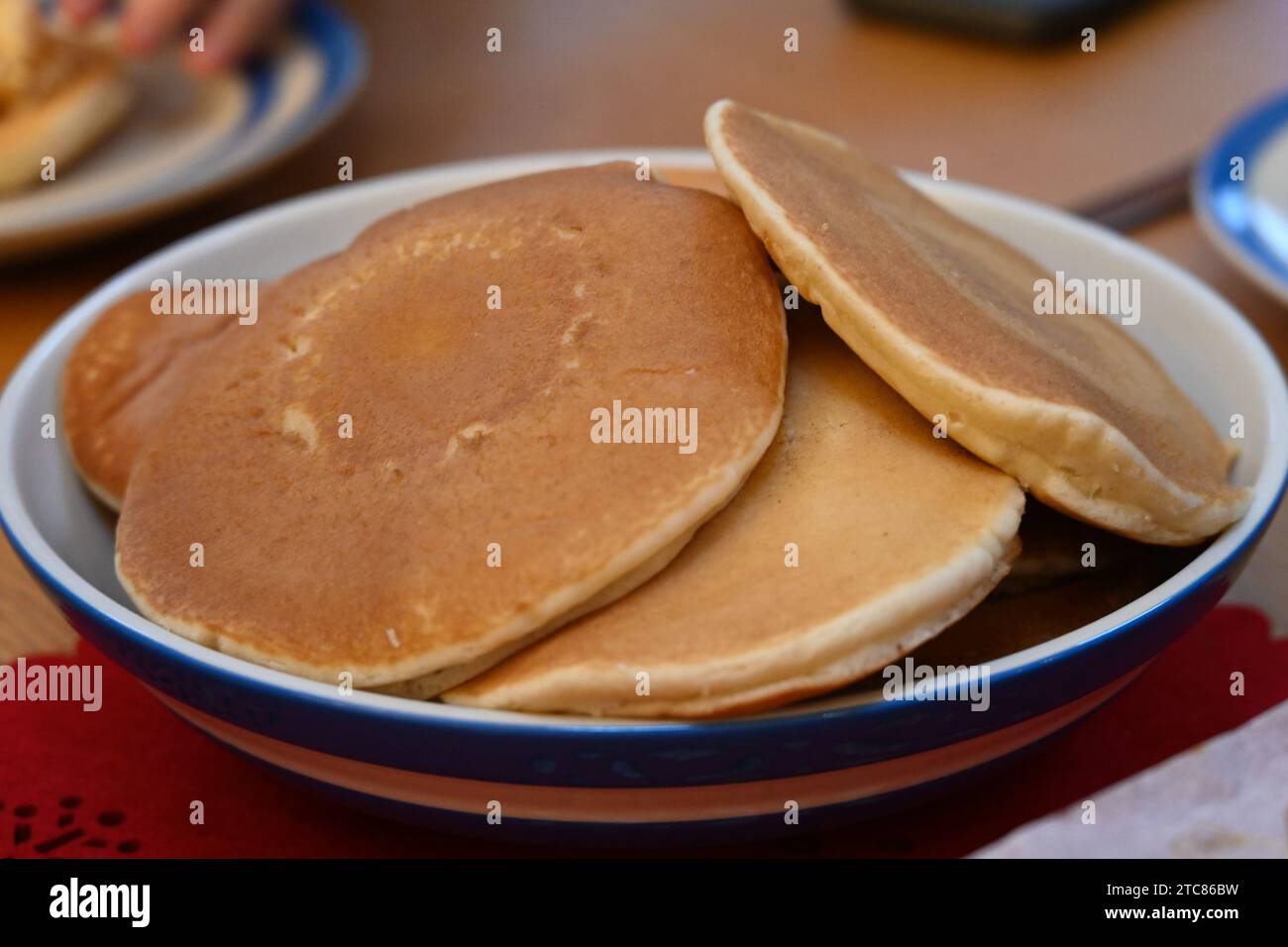 Una ciotola di pancake americani impilati in alto pronti da mangiare e conditi con sciroppo d'acero Foto Stock