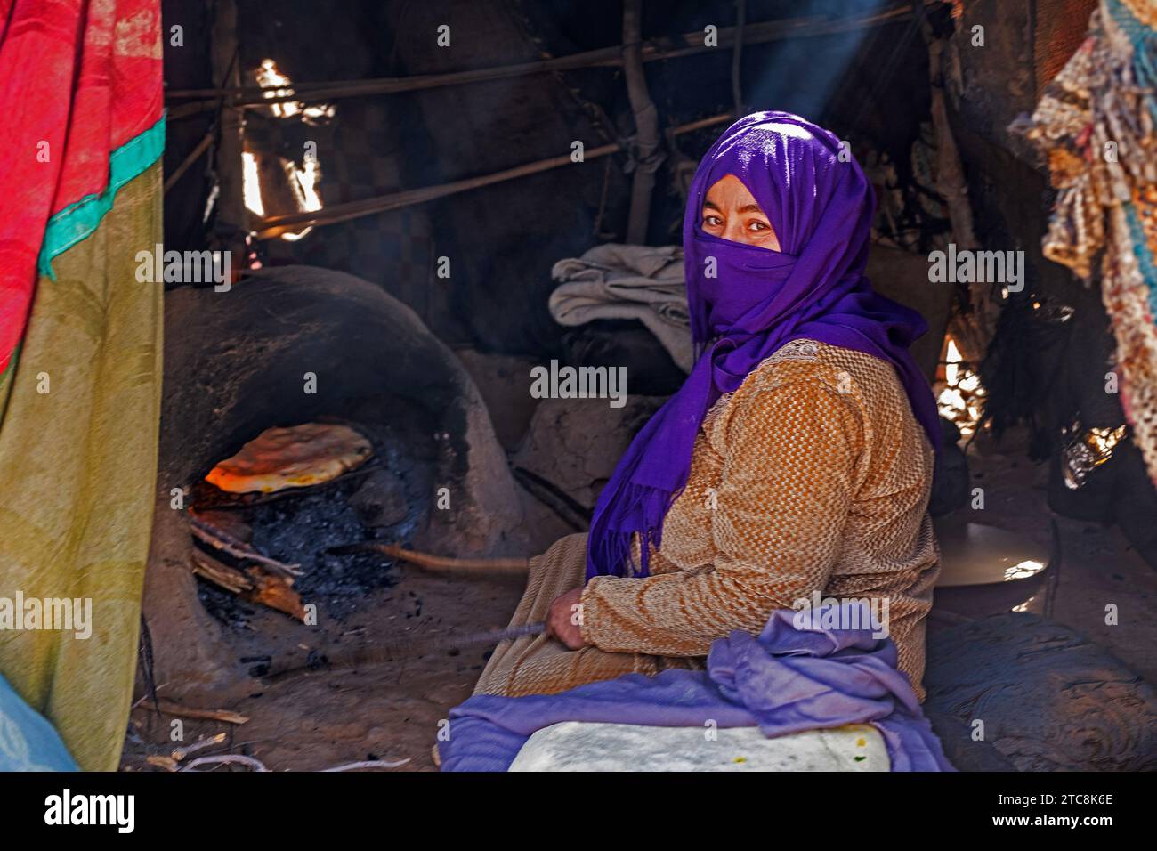 Donna nomade beduina con hijab che prepara pane nel forno tradizionale in tenda nel deserto del Sahara vicino a Merzouga, Drâa-Tafilalet, Errachidia, Marocco Foto Stock