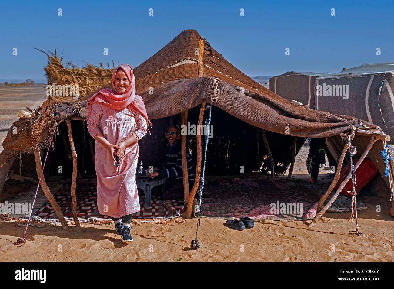 Donna nomade beduina con hijab e uomo che serve tè in tenda nel deserto del Sahara vicino a Merzouga, Drâa-Tafilalet, Errachidia, Marocco Foto Stock
