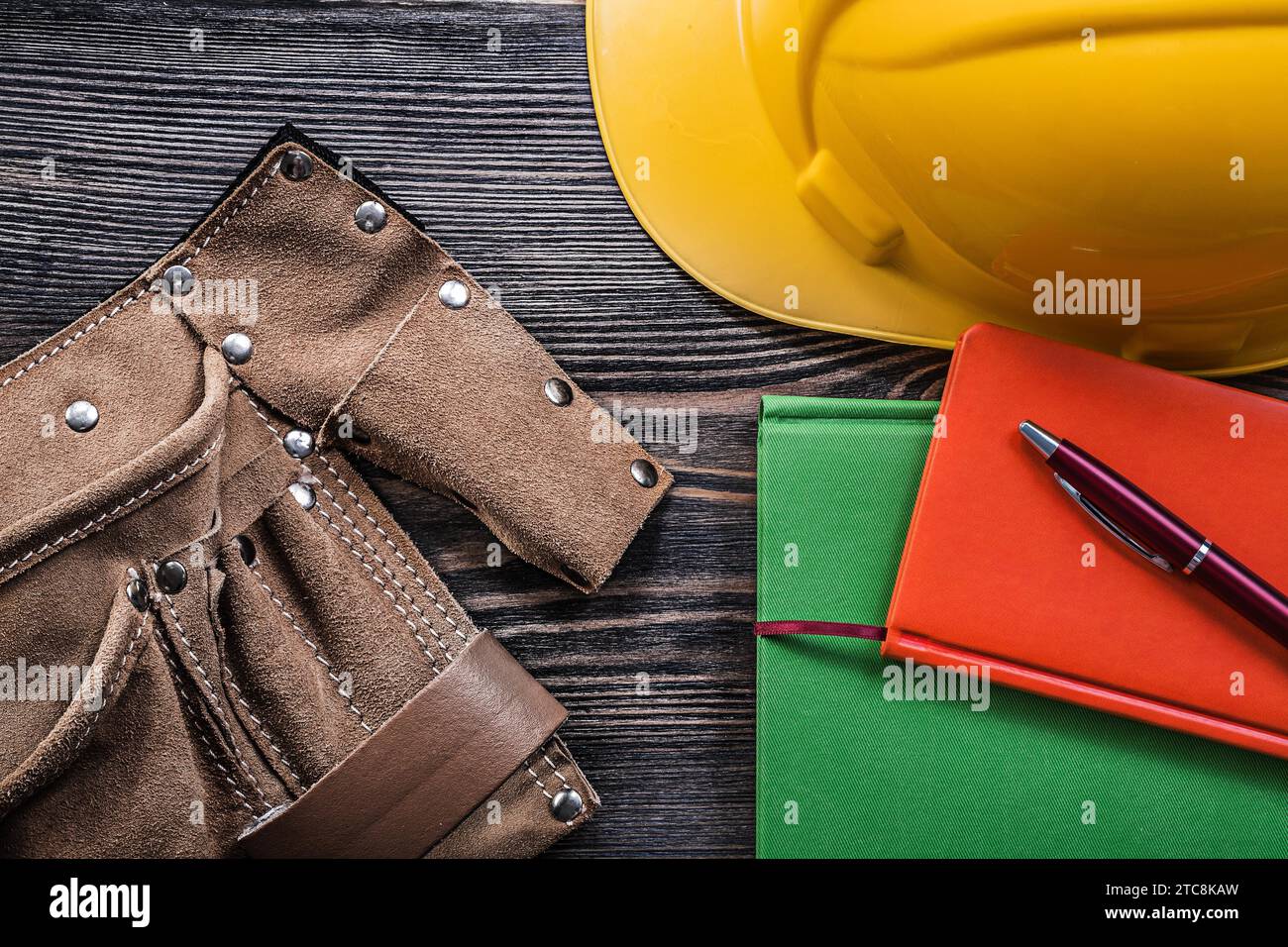 Composizione della cintura portautensili note-book casco da costruzione penna su tavola di legno concetto di costruzione Foto Stock