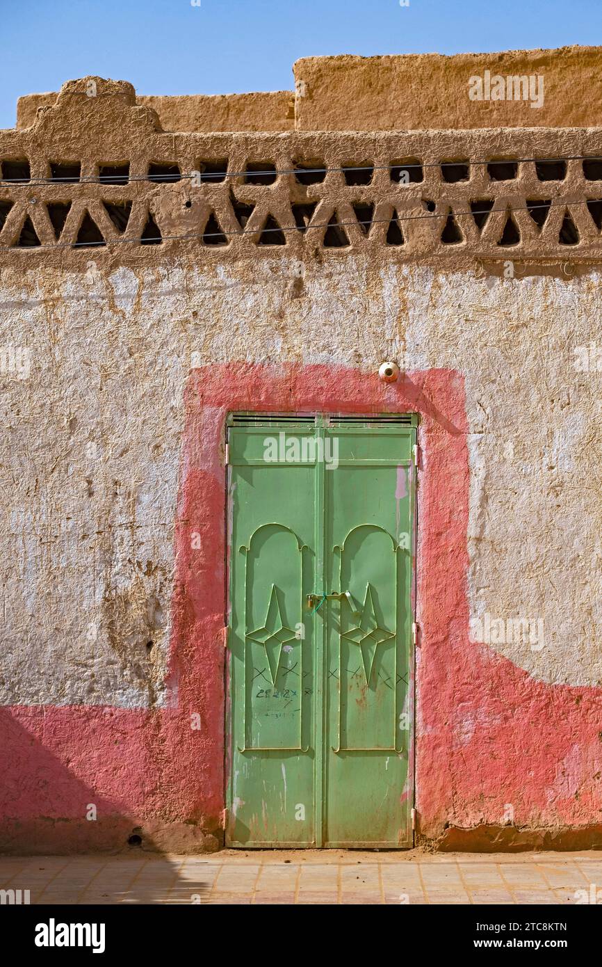 Porta in ferro verde nel muro di una casa tradizionale fatta di fango e paglia nel villaggio di Merzouga nel deserto del Sahara, Drâa-Tafilalet, Errachidia, Marocco Foto Stock