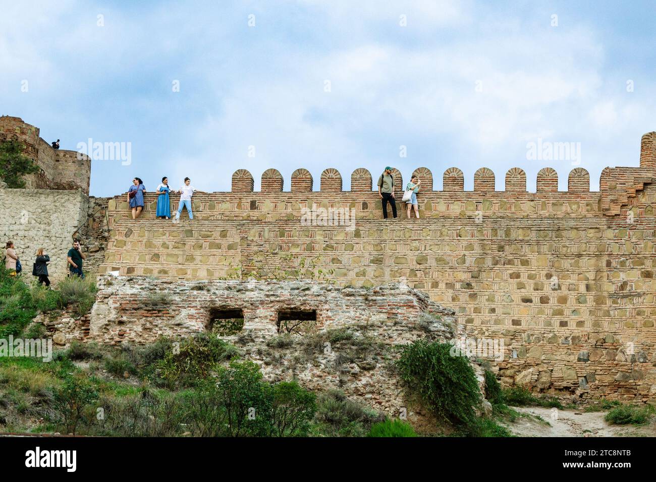 Tbilisi, Georgia - 23 settembre 2023: Persone sulle mura dell'antica fortezza di Narikala sulla collina di Sololaki nella città di Tbilisi al crepuscolo serale autunnale Foto Stock