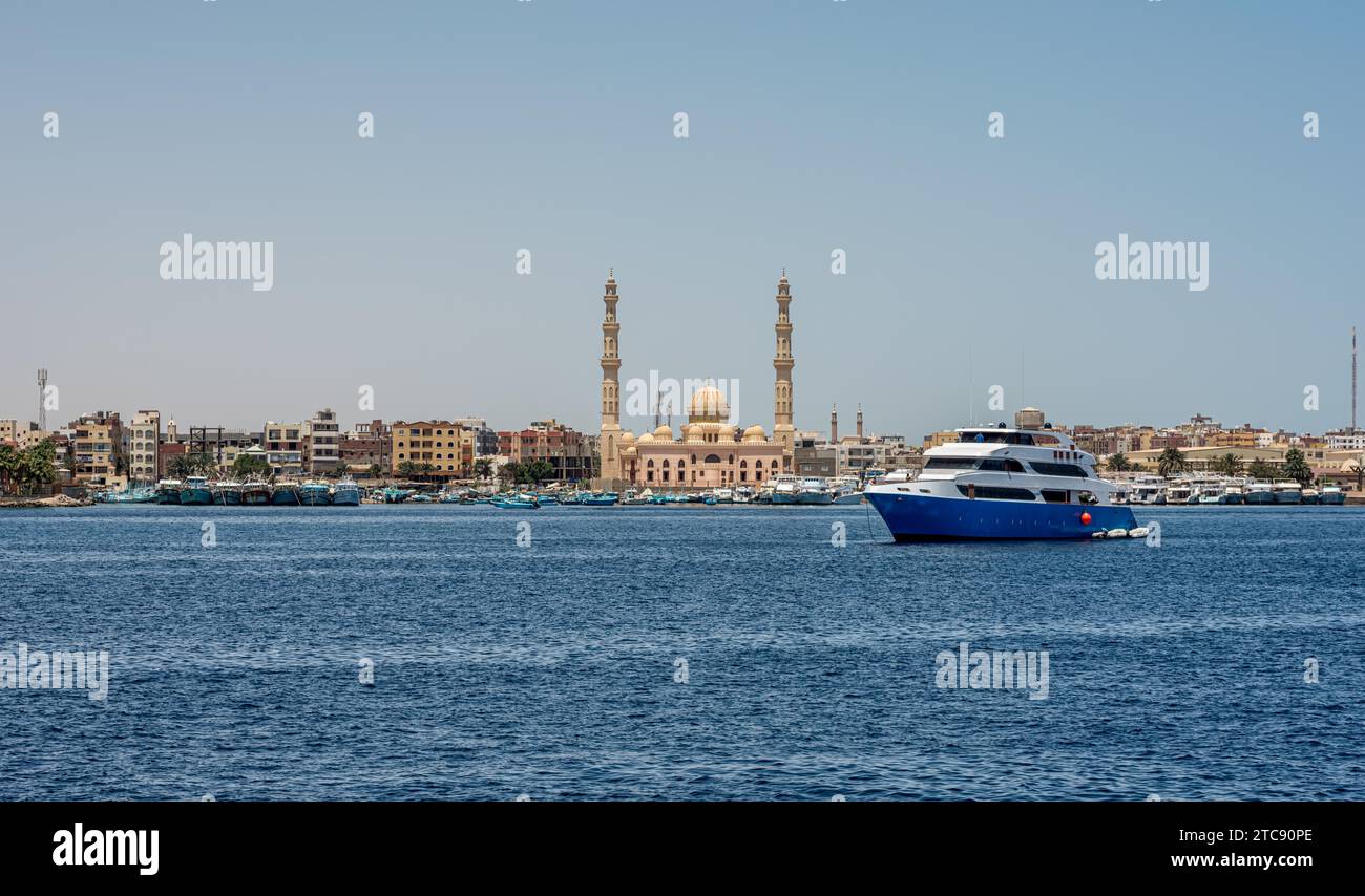 Barca vicino alla riva del Mar Rosso sullo sfondo della città di edifici e moschee in Egitto Foto Stock