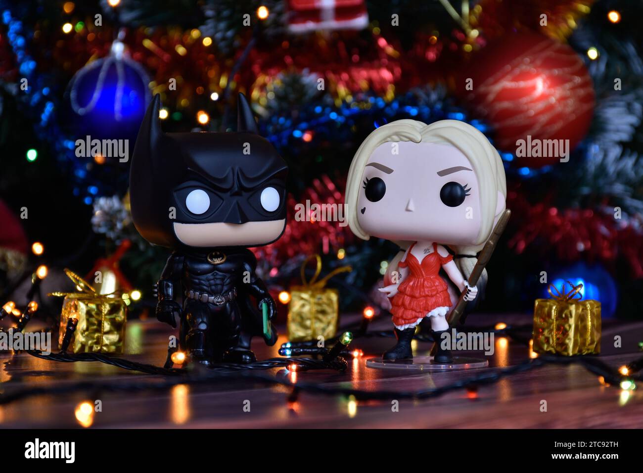 Funko Pop action figure dei supereroi dei fumetti DC Batman e Harley Quinn. Albero di Natale, ornamenti, ghirlanda, confezioni regalo, luci colorate. Foto Stock