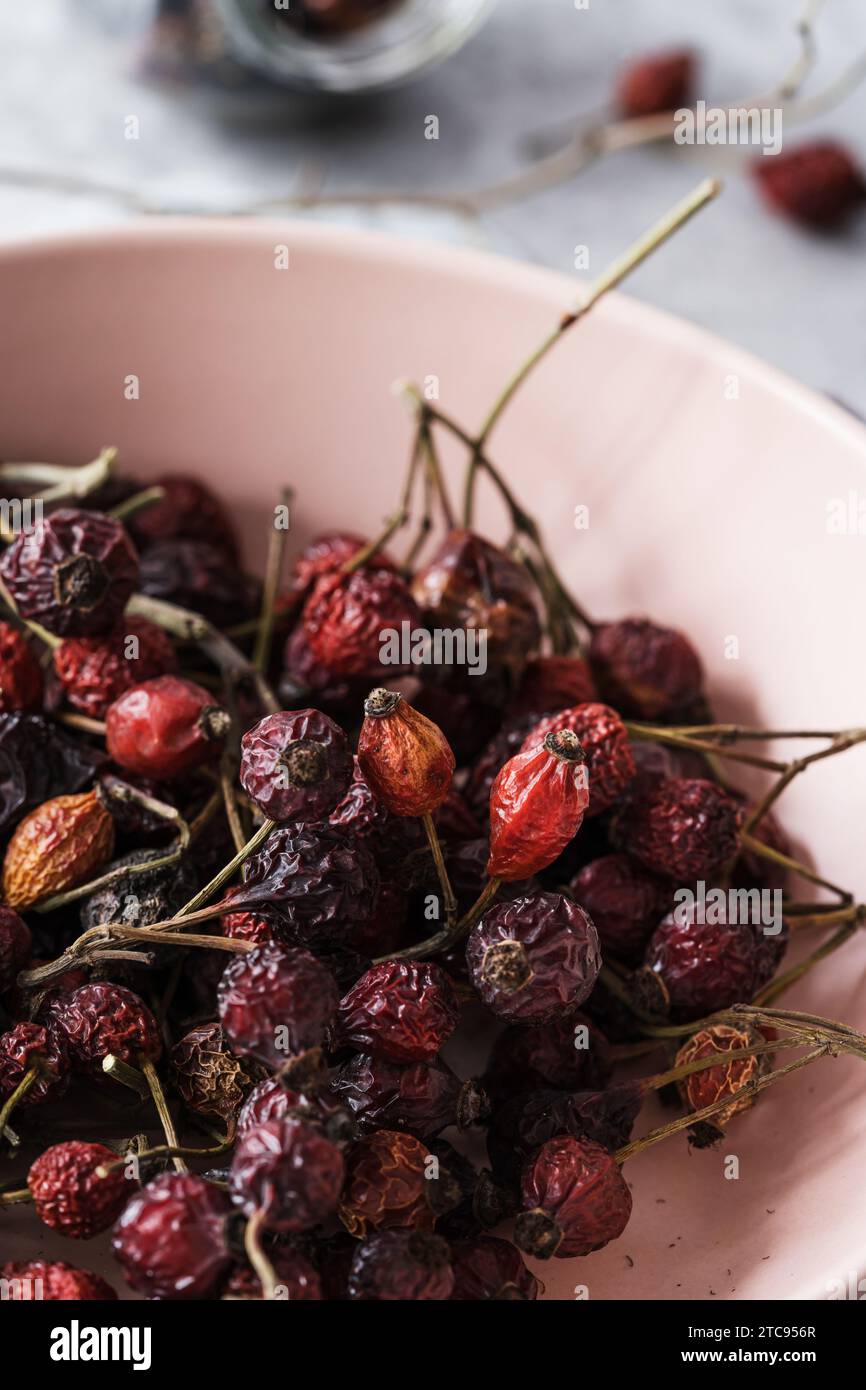 Bacche di rosa organiche essiccate al sole in ciotola rosa, risorse ecologiche sane e sostenibili, pronte a preparare il tè alle erbe Foto Stock