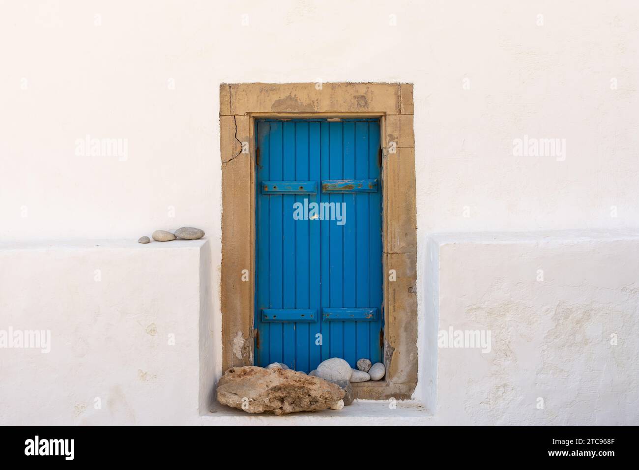 Tradizionali persiane blu e pareti imbiancate sul lato di un vecchio edificio greco. Foto Stock