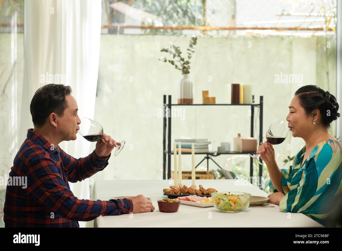 Coppia vietnamita anziana che cena e beve vino a casa Foto Stock