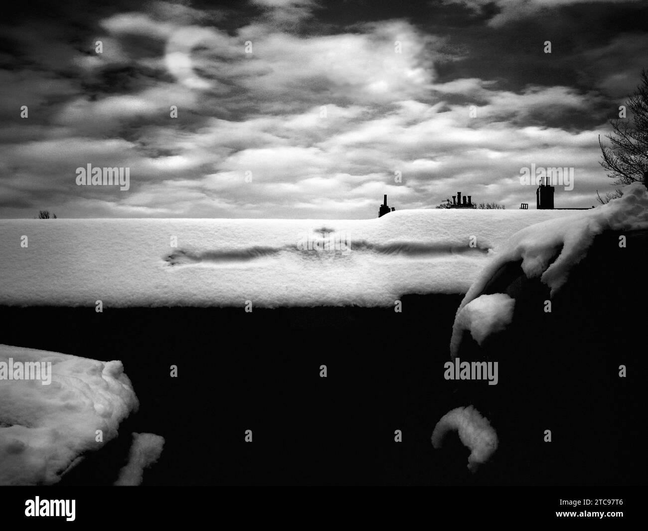 Il giorno di Natale, scenografico spettacolo di strade innevate al crepuscolo e vasi vittoriani, con cielo scuro e nuvole bianche pesanti e una luna a mezzaluna. Parete inclinata ricoperta di neve con l'impronta del viso di un bambino e braccia allungate. Foto Stock