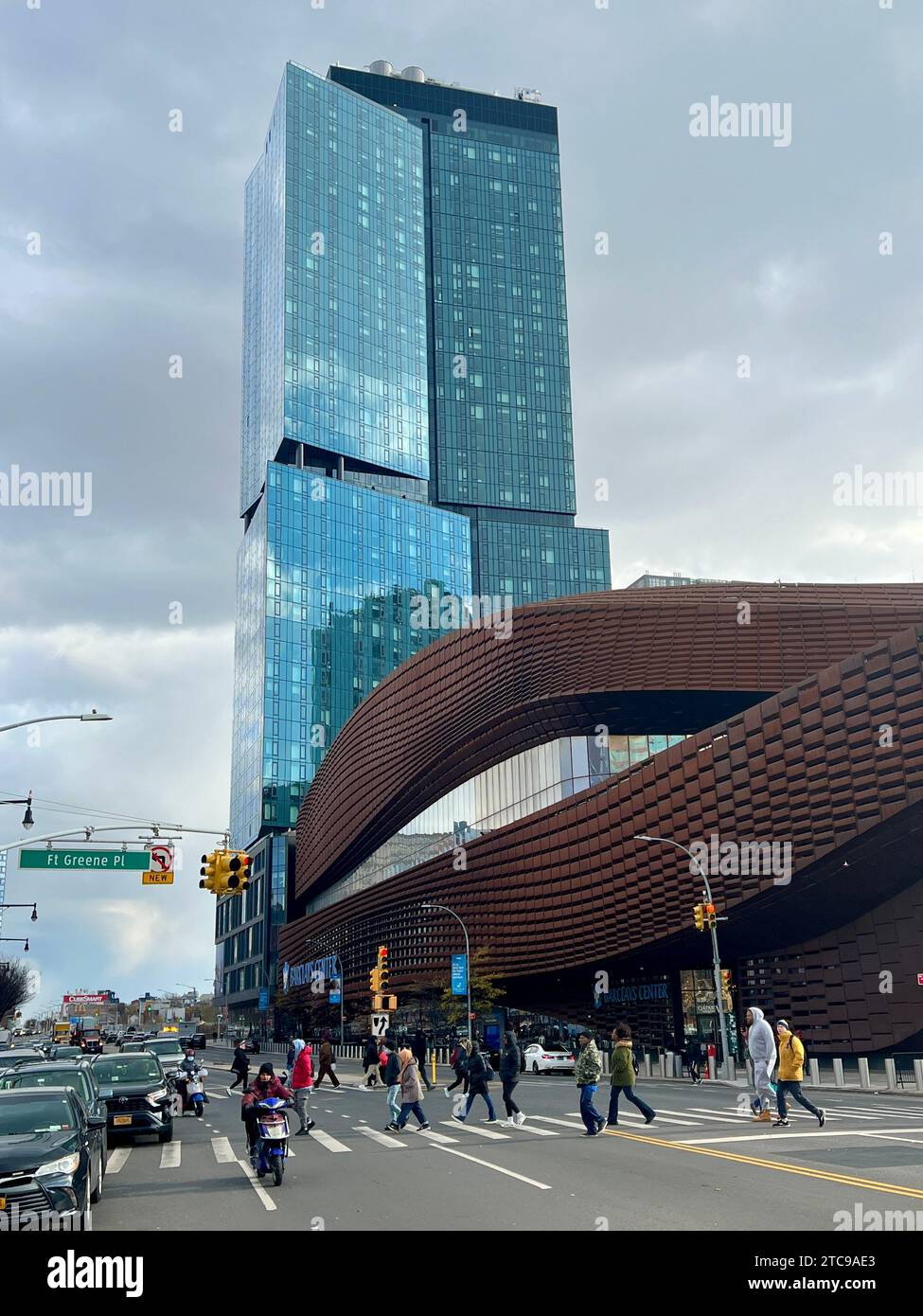 I pedoni attraversano Atlantic Avenue presso il Barklays Center con un alto edificio di vetro dietro entrambi che riflettono il nuovo volto in continua crescita di Brooklyn, New York City. Foto Stock