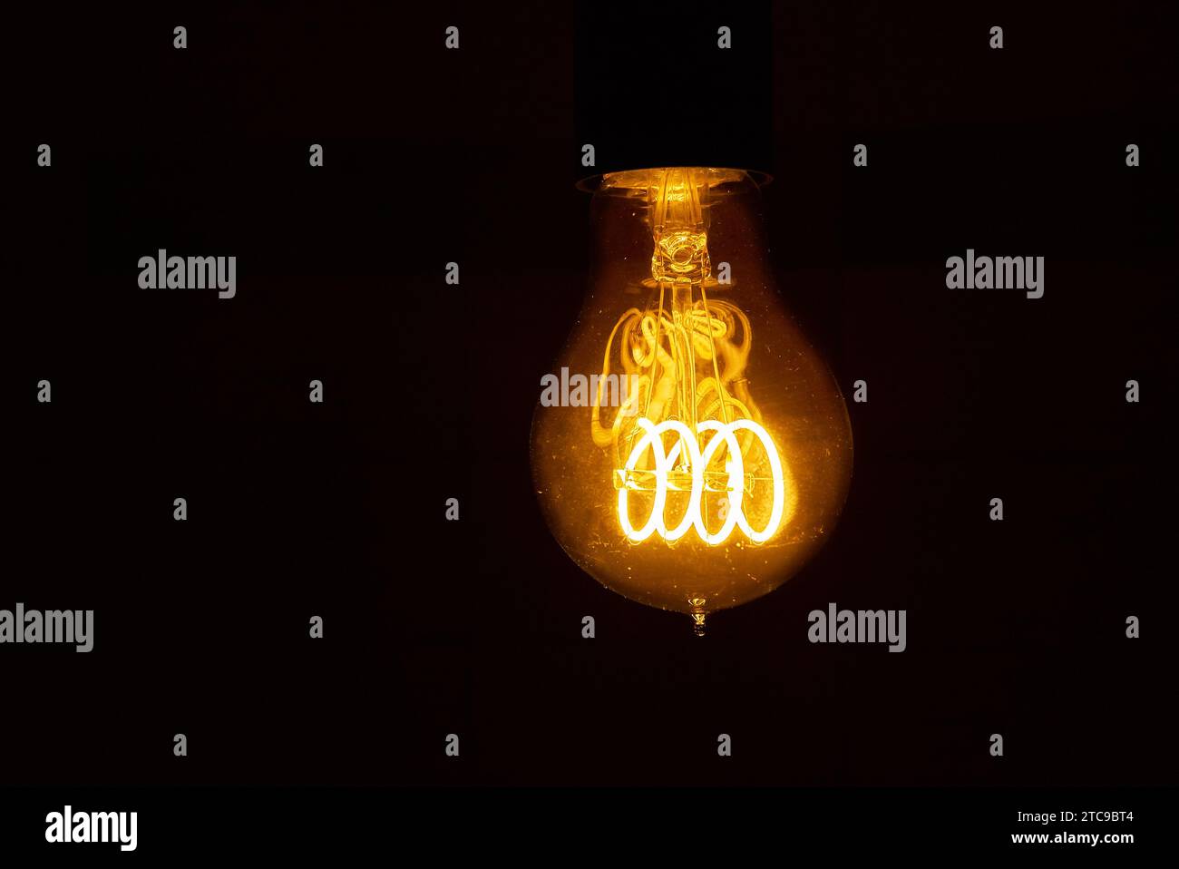 Lampadina a incandescenza radiante che illumina l'oscurità con luce calda di notte Foto Stock