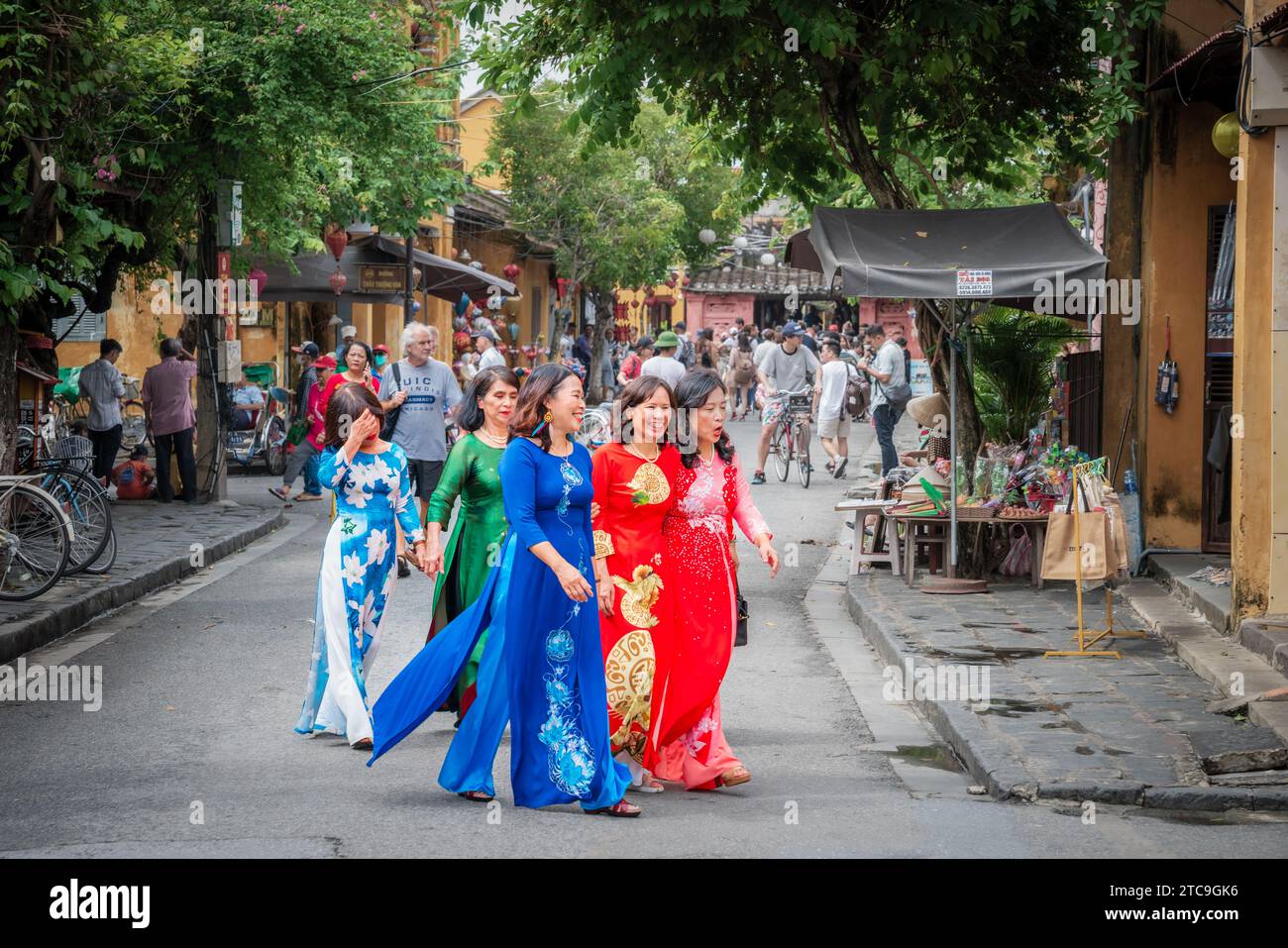 Hoi An, Vietnam, 20 novembre 2022: Un gruppo di donne vietnamite in abiti tradizionali che camminano in una strada trafficata di Hoi An, Vietnam Foto Stock