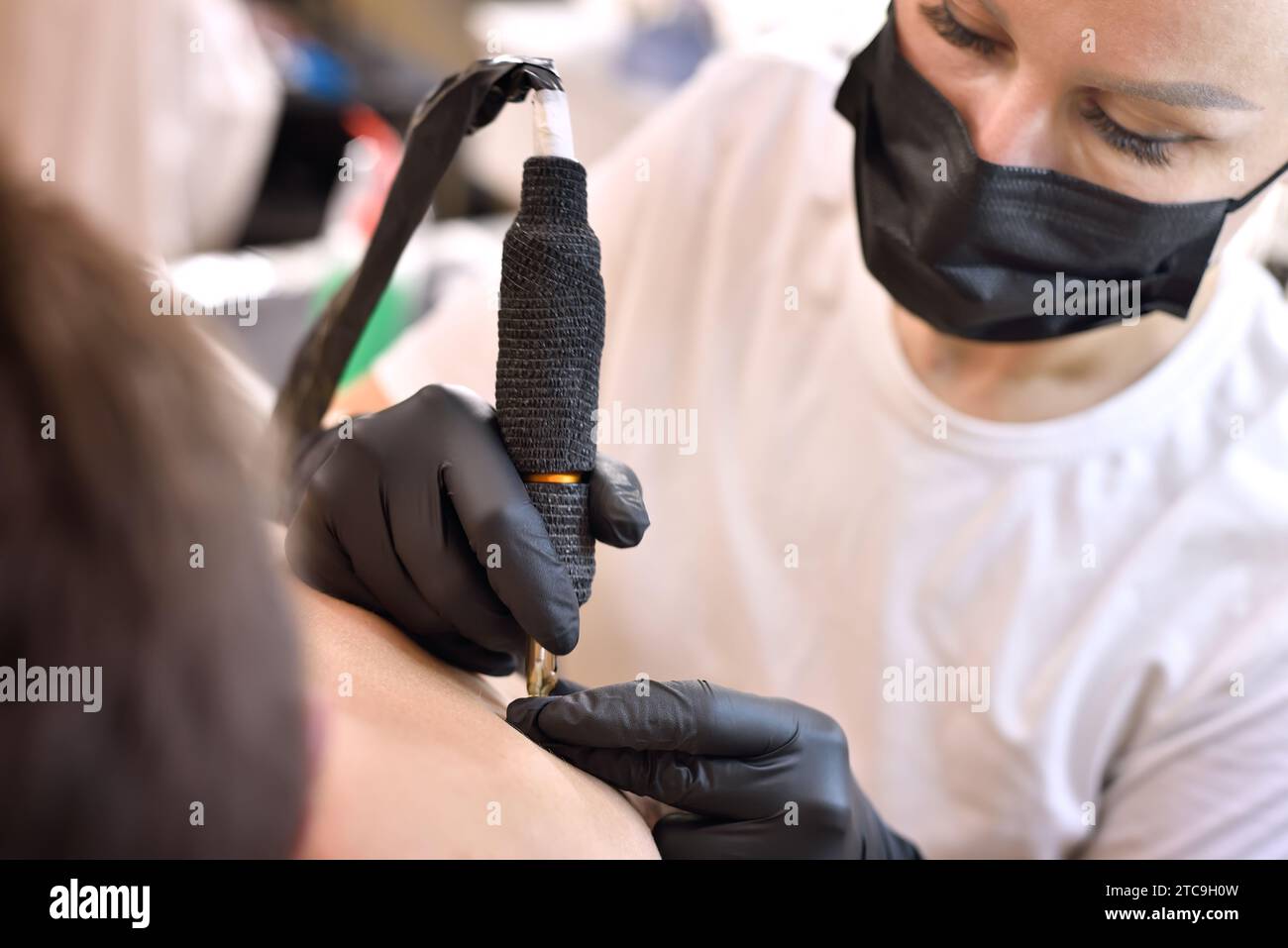 Tatuatore donna professionista che brucia tatuaggio sulla schiena dell'uomo. Concetto di arte e design. Primo piano Foto Stock