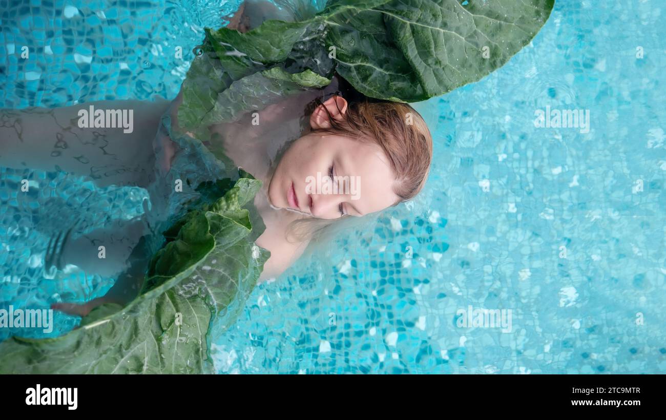 ritratto di una sensuale e seducente giovane donna matura in acqua tra grandi foglie di piante verdi, nella piscina benessere della spa. Trattamento di bellezza della pelle, copia spa Foto Stock