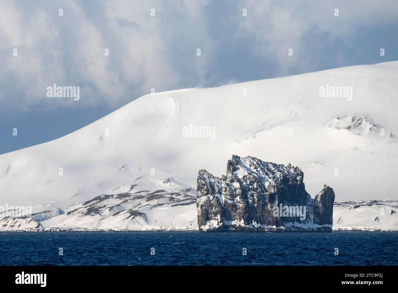 Antartide, Isole Shetland meridionali, stretto di Bransfield. New Rock con vista costiera dell'isola di Deception in lontananza Foto Stock