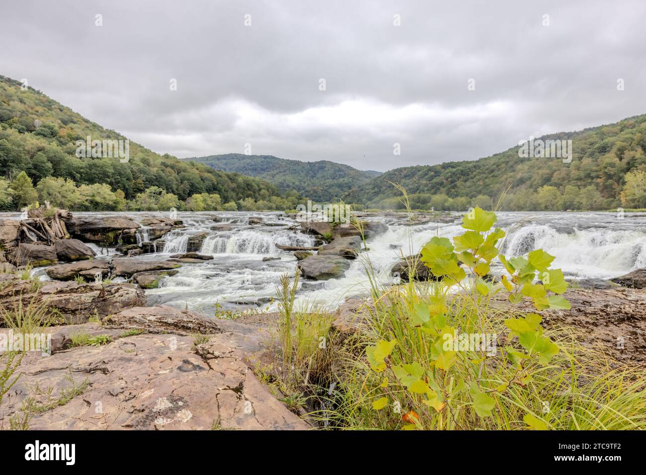 Una vista panoramica di una cascata circondata da sponde rocciose con un fiume che scorre attraverso il paesaggio Foto Stock