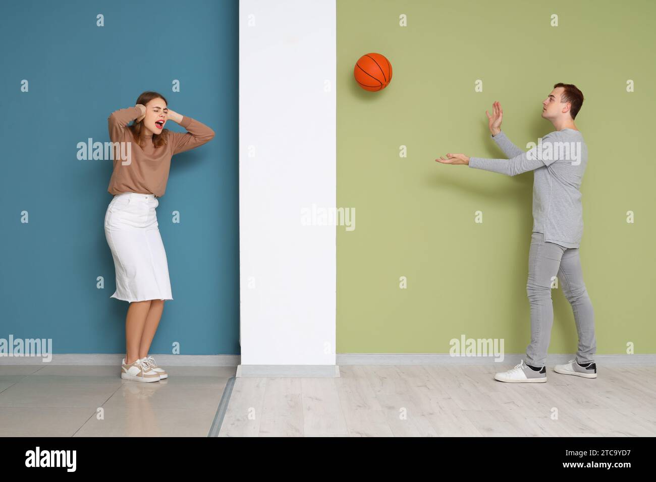Giovane donna che soffre di vicino rumoroso che gioca con la palla a casa Foto Stock