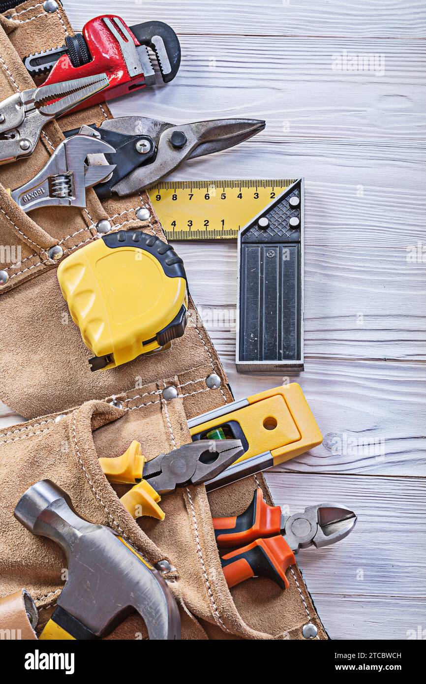 Concetto di manutenzione per utensili da costruzione nella cintura portautensili su un pannello di legno Foto Stock