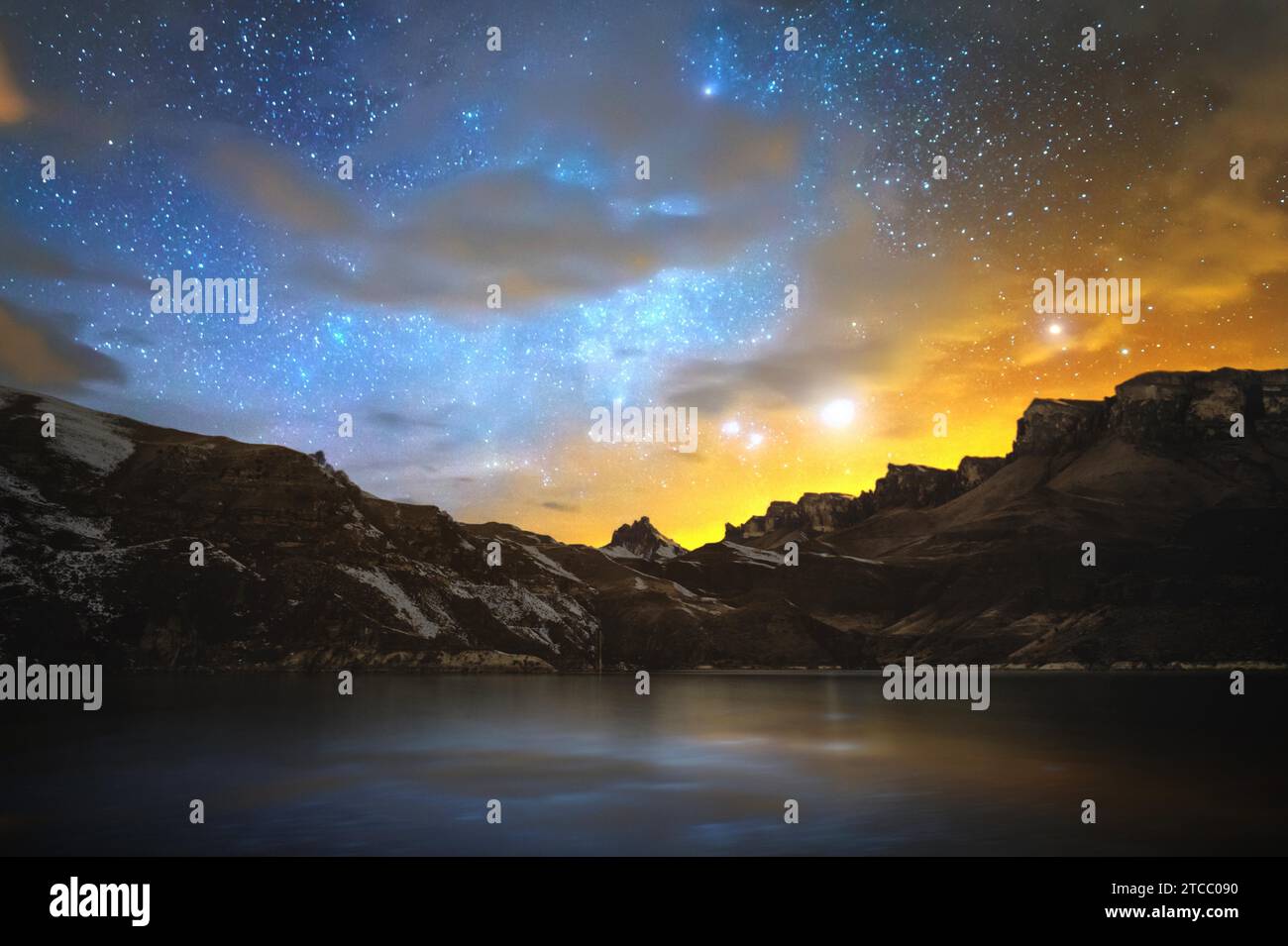 Lago di alta montagna nel Caucaso settentrionale, circondato da rocce epiche e un luminoso cielo stellato invernale al tramonto. Scenario notturno a lunga esposizione. Magia Foto Stock