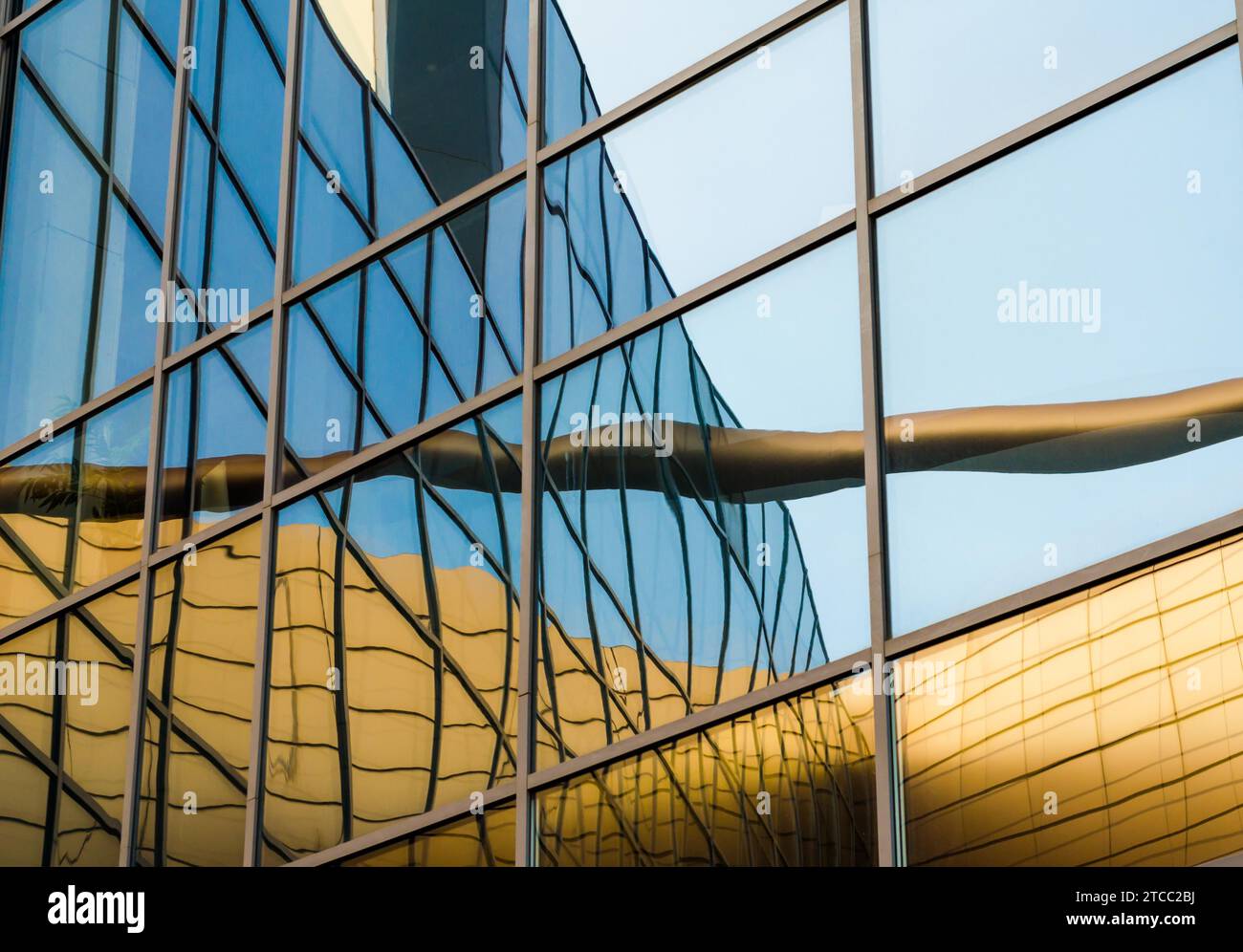 Riflesso distorto di un edificio giallo nelle finestre a specchio di un edificio per uffici Foto Stock