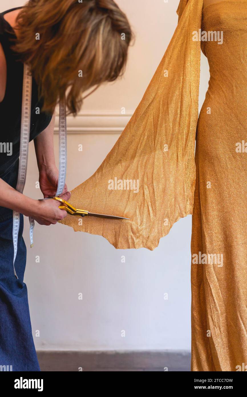 Stilista di moda che utilizza forbici tessili per lavorare sul design dell'abbigliamento. Shot verticale Foto Stock