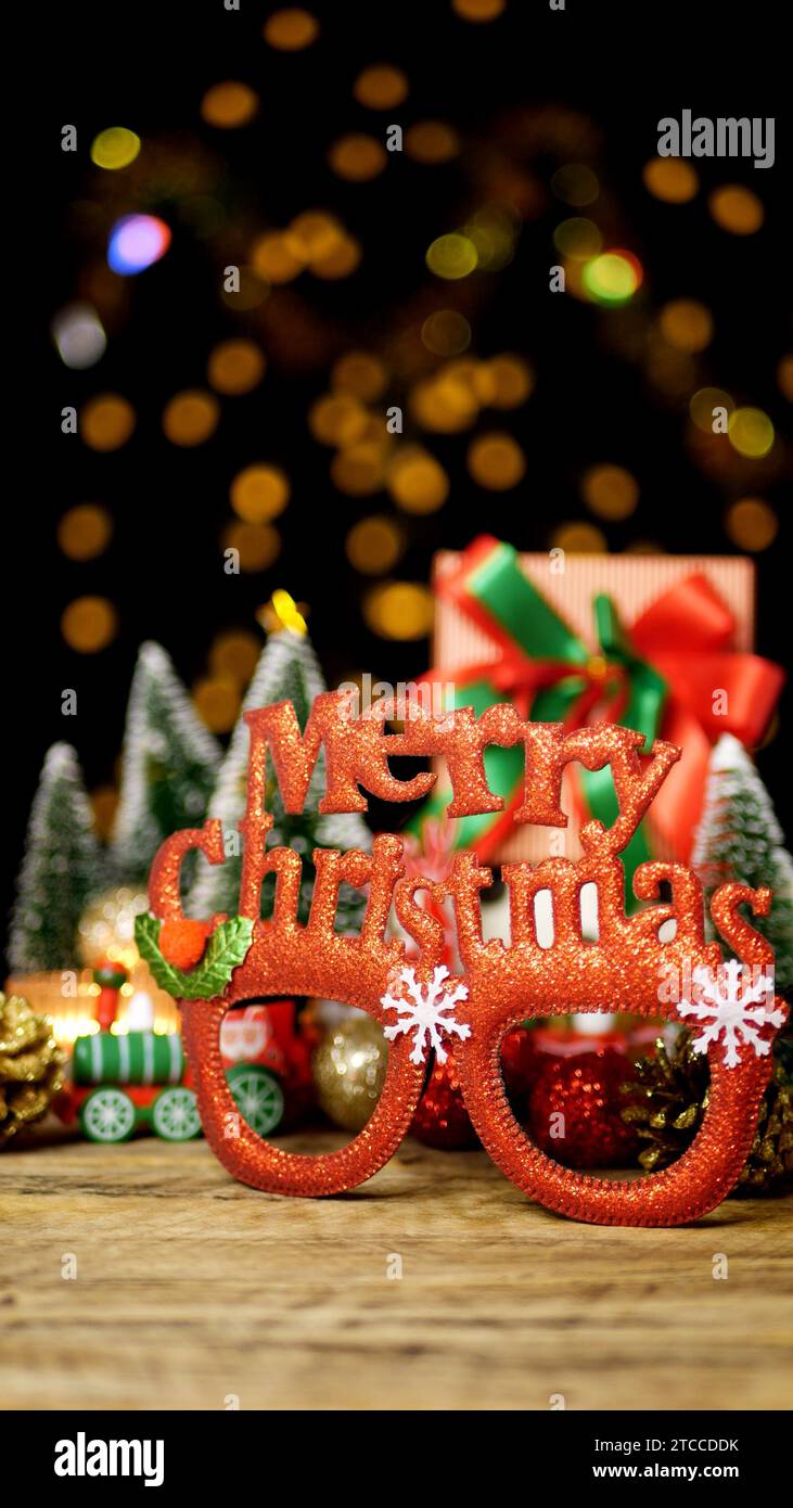Confezione regalo di Natale con occhiali da festa di Natale su tavolo in legno con decorazioni natalizie durante i saluti di stagione Foto Stock