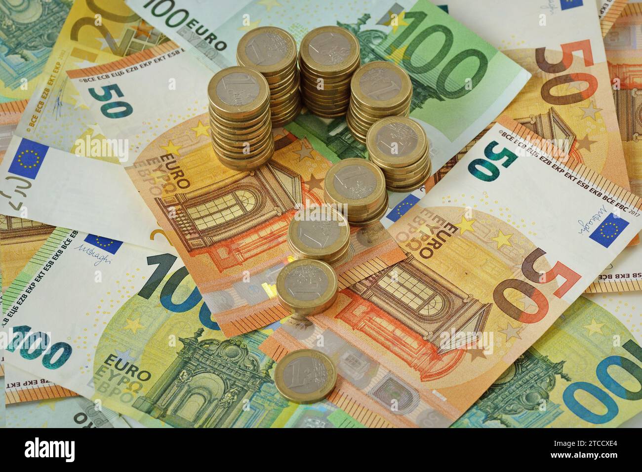 Punto interrogativo delle monete in euro impilate sulle banconote in euro - concetto di moneta, incertezza ed emissioni finanziarie Foto Stock