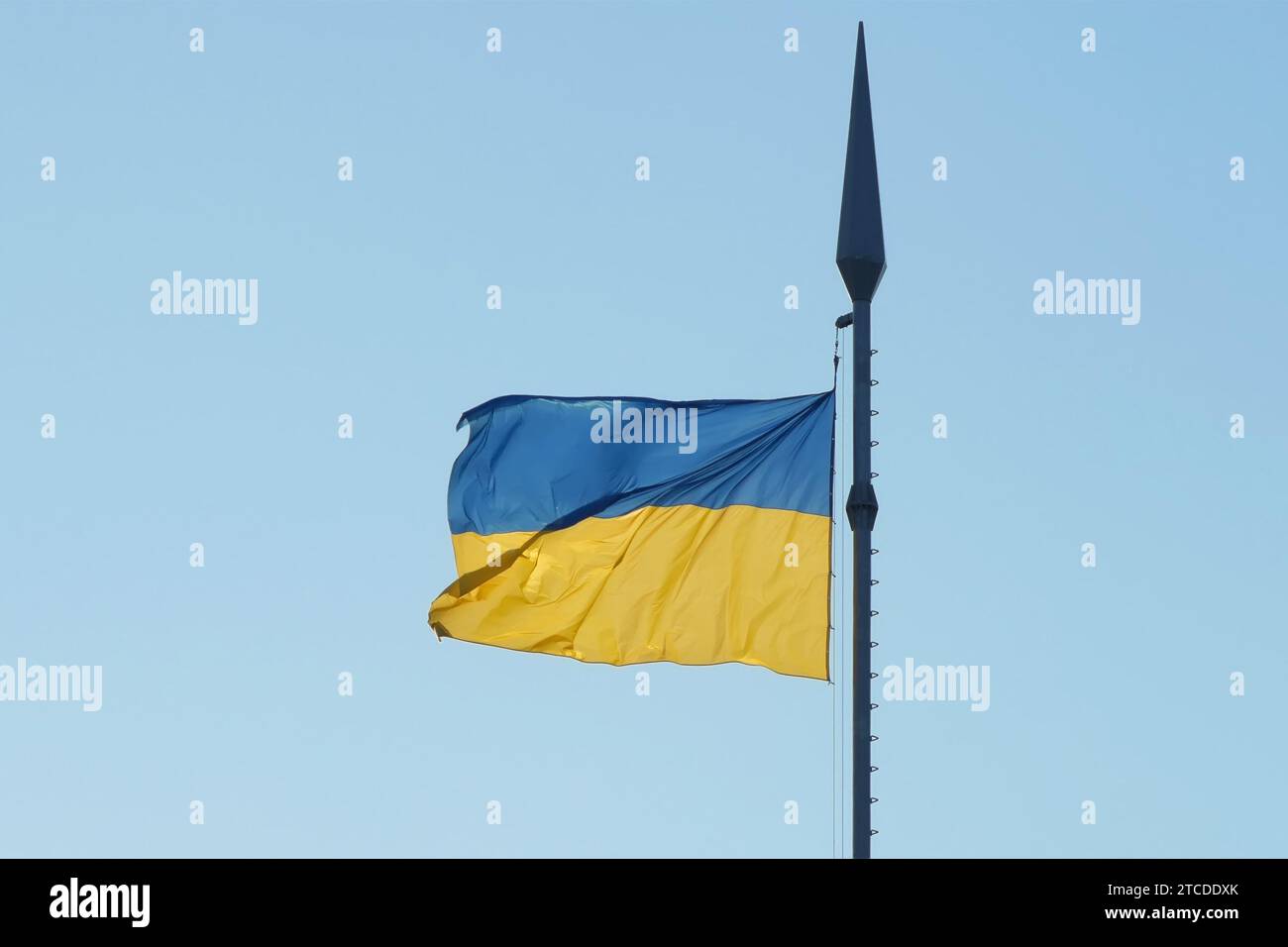 La bandiera nazionale dell'Ucraina fluttua nel vento su un'asta di bandiera alta in retroilluminazione alla luce del sole Foto Stock