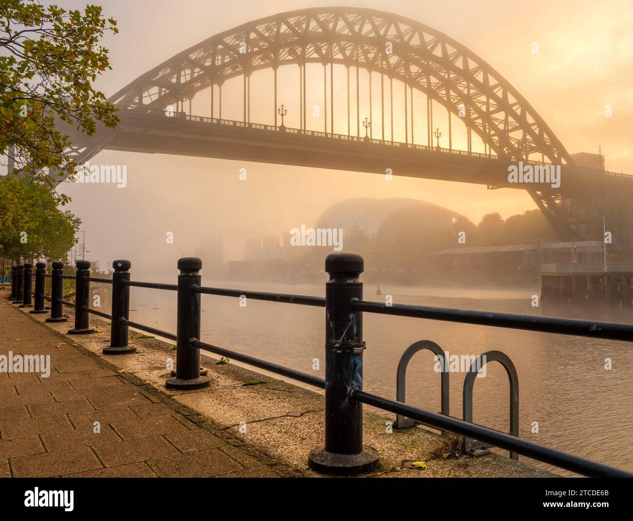 Tyne Bridge e Quayside su un moring dorato e nebbioso in autunno.incorniciato da ringhiere. Foto Stock