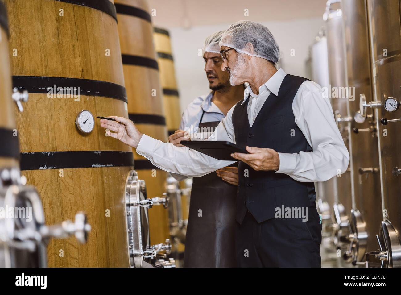 Produttore di vino professionista che lavora in una grande azienda vinicola moderna liquori bevande alcoliche industria controllo qualità e fermentazione monitor colore vintage a. Foto Stock