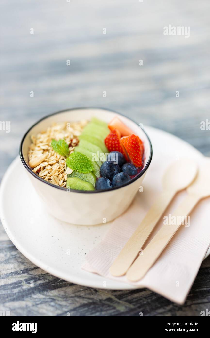 Ciotola del pasto mattutino con vitamine e fibre, ricco di cibo sano. miscela colorata di frutti di bosco con shot verticale di cereali a base di cereali. Foto Stock