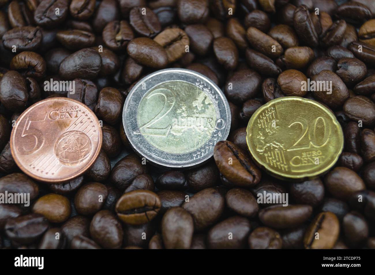 Chicchi di caffè con monete in euro, aumento del prezzo del caffè Foto Stock