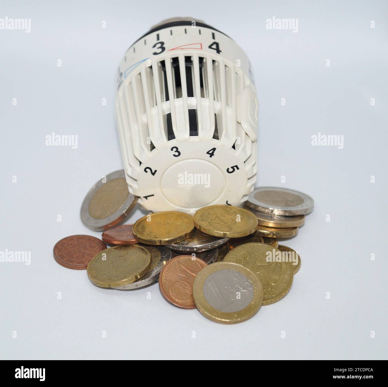 Valvola termostatica di un riscaldatore con monete Euro, simbolo immagine costi di riscaldamento Foto Stock