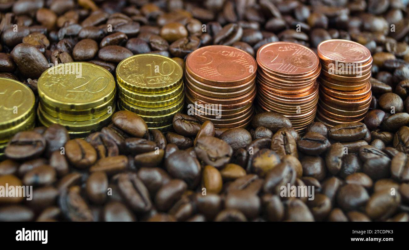 Chicchi di caffè tostati con pile di monete Euro, prezzo del caffè Foto Stock