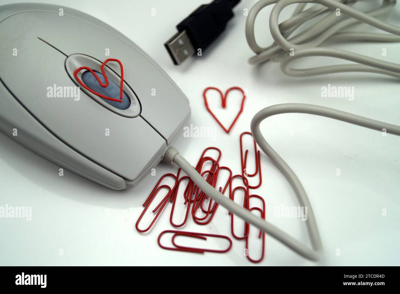 mouse per computer con graffette rosse, due delle quali a forma di cuore, amore in ufficio Foto Stock