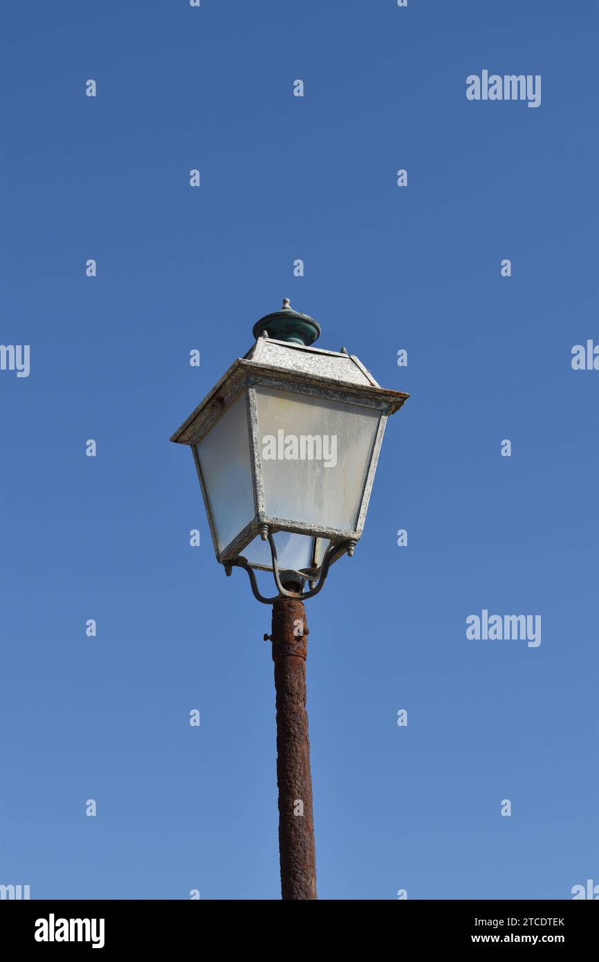 Una lanterna in acciaio corroso con pannelli di vetro nuvolosi su un palo arrugginito marrone Foto Stock