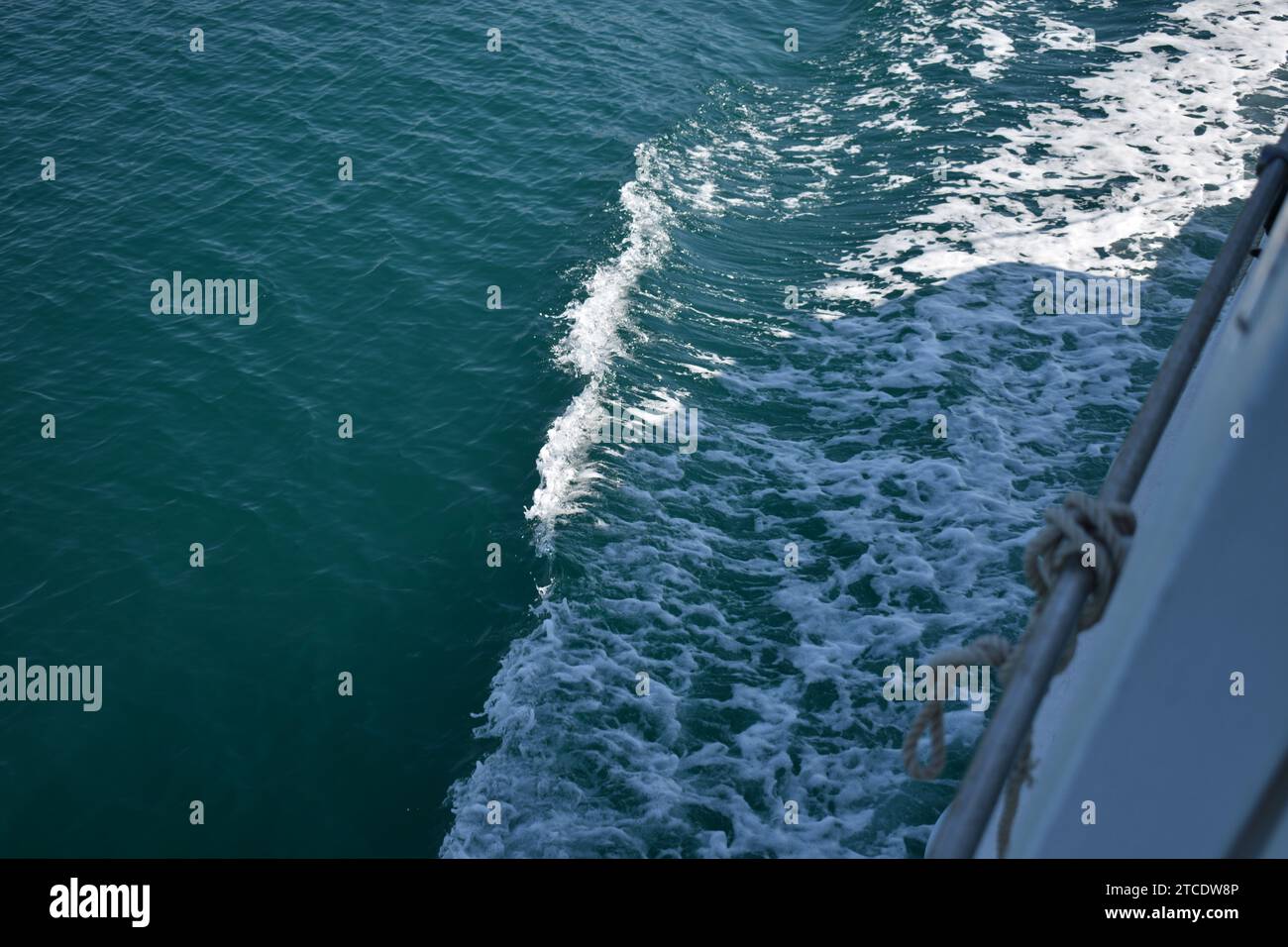 La schiuma bianca sull'acqua di mare viene spinta via da una barca in movimento Foto Stock