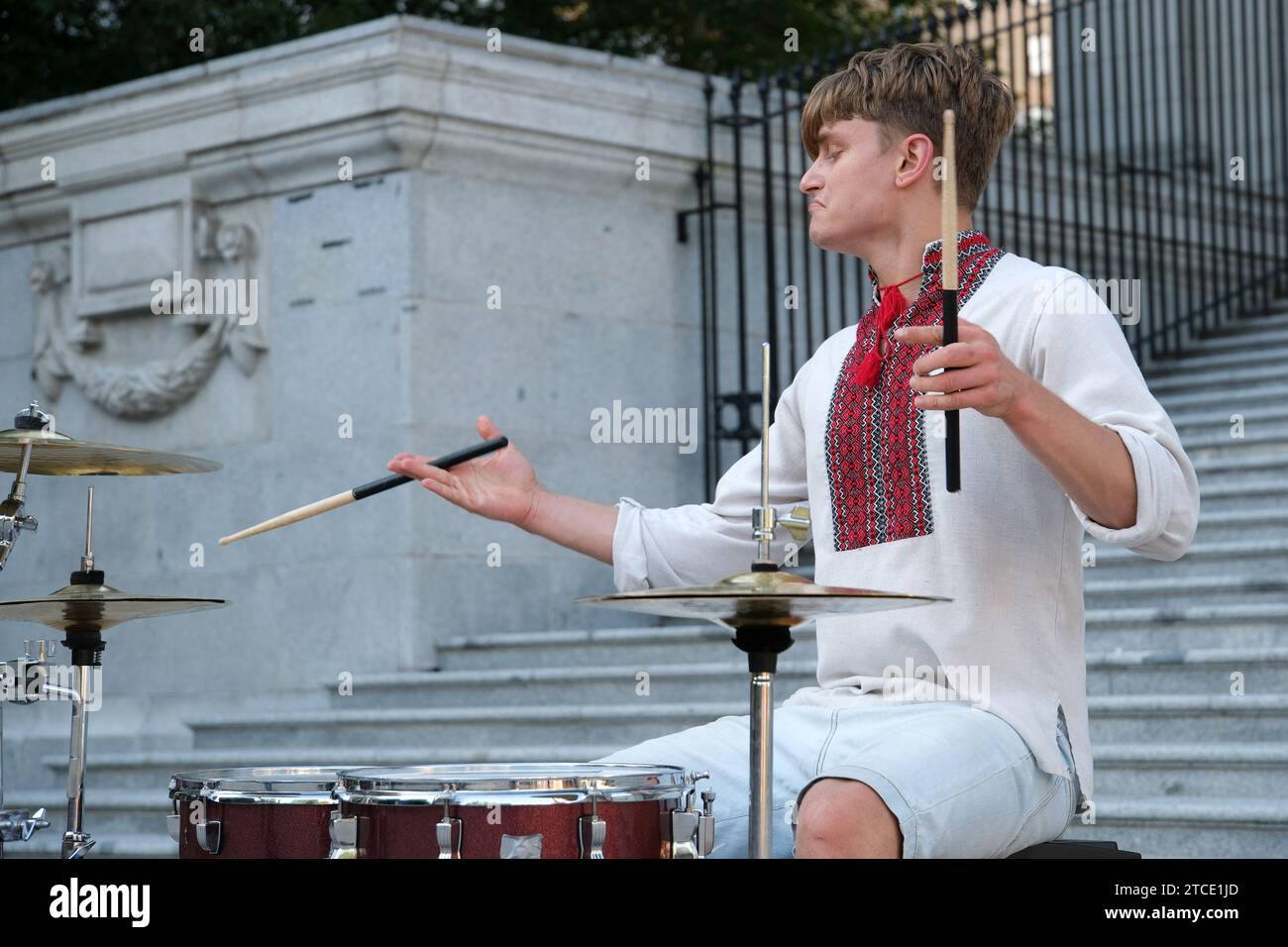 Giocate magistralmente il bellissimo ragazzo di aspetto europeo con la camicia ricamata Ucraina abiti nazionali dell'Ucraina suonano i bastoncini del tamburo. potere della felicità professionalità Foto Stock