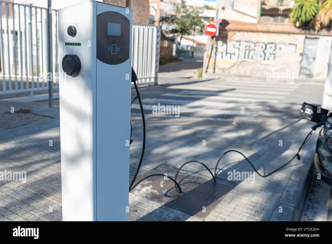 Caricabatterie collegato all'auto elettrica su strade pubbliche. Foto Stock