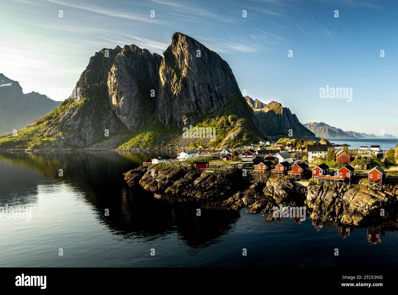 Il borgo di Hamnøya con il suo rorbuer rosso all'ombra di Festhæltinden preso dal sole estivo tarda sera Foto Stock