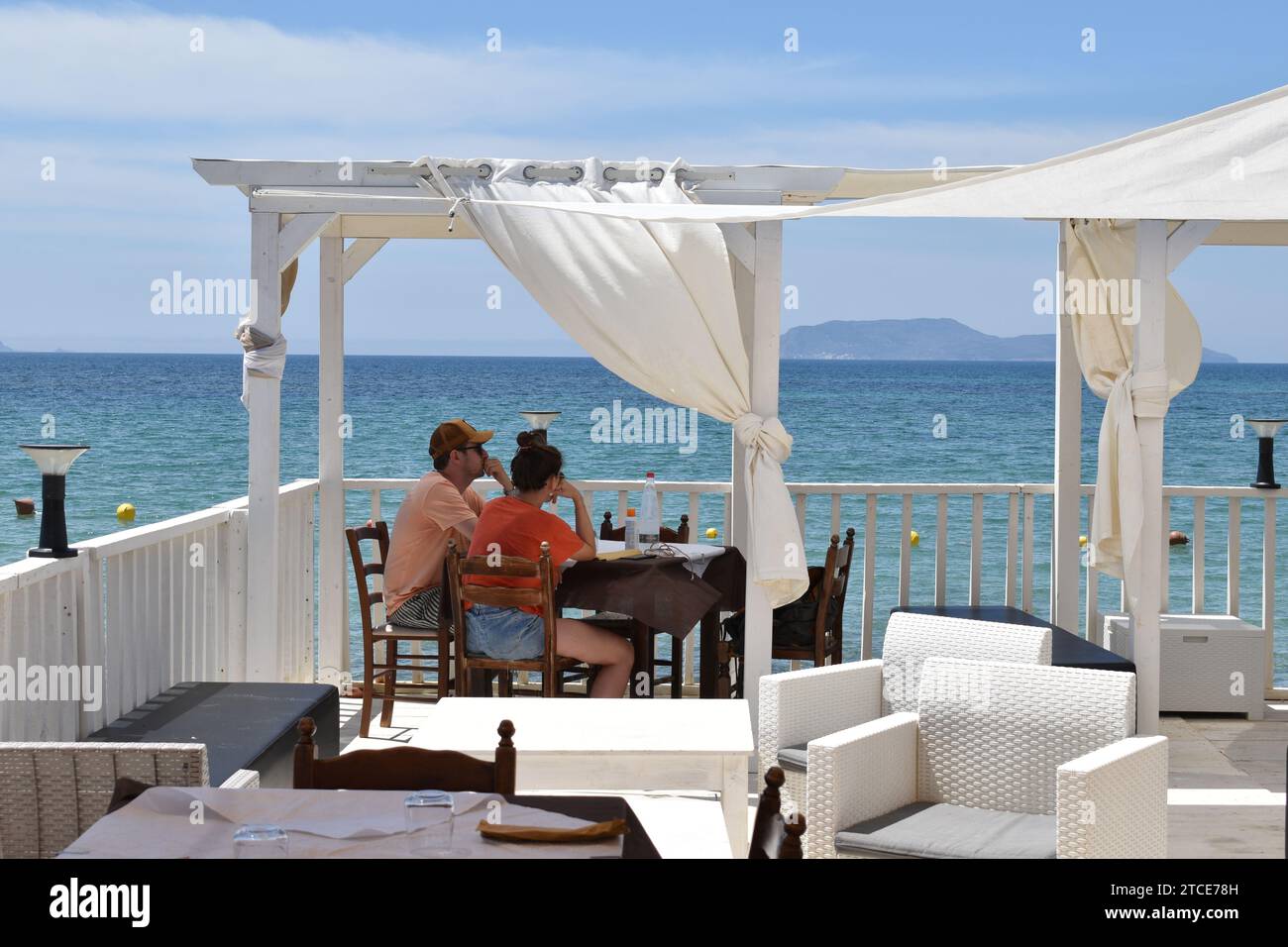 Giovani coppie sedute ad un tavolo con vista sul Mar Mediterraneo nel ristorante siciliano Lido Playa De Rio nel villaggio di San Teodoro Foto Stock