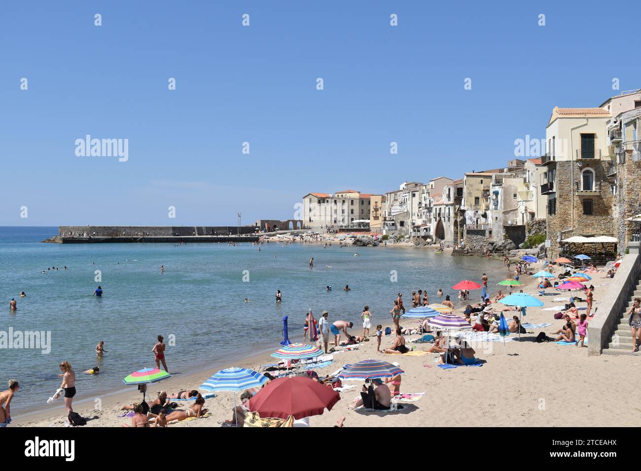 Persone che si godono una giornata di sole sulla spiaggia della città costiera di Cefalù, in Sicilia Foto Stock