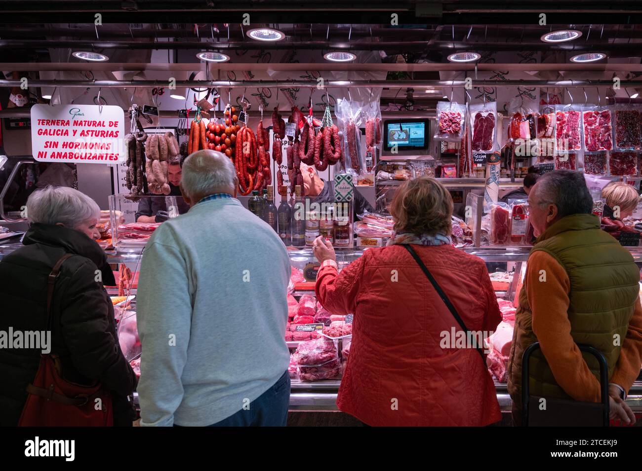 Gente che compra in una bancarella di carne nel mercato centrale di Alicante. I compratori approfittano dell'opportunità di acquistare pesce per i pasti e le cene per l'upcomin Foto Stock