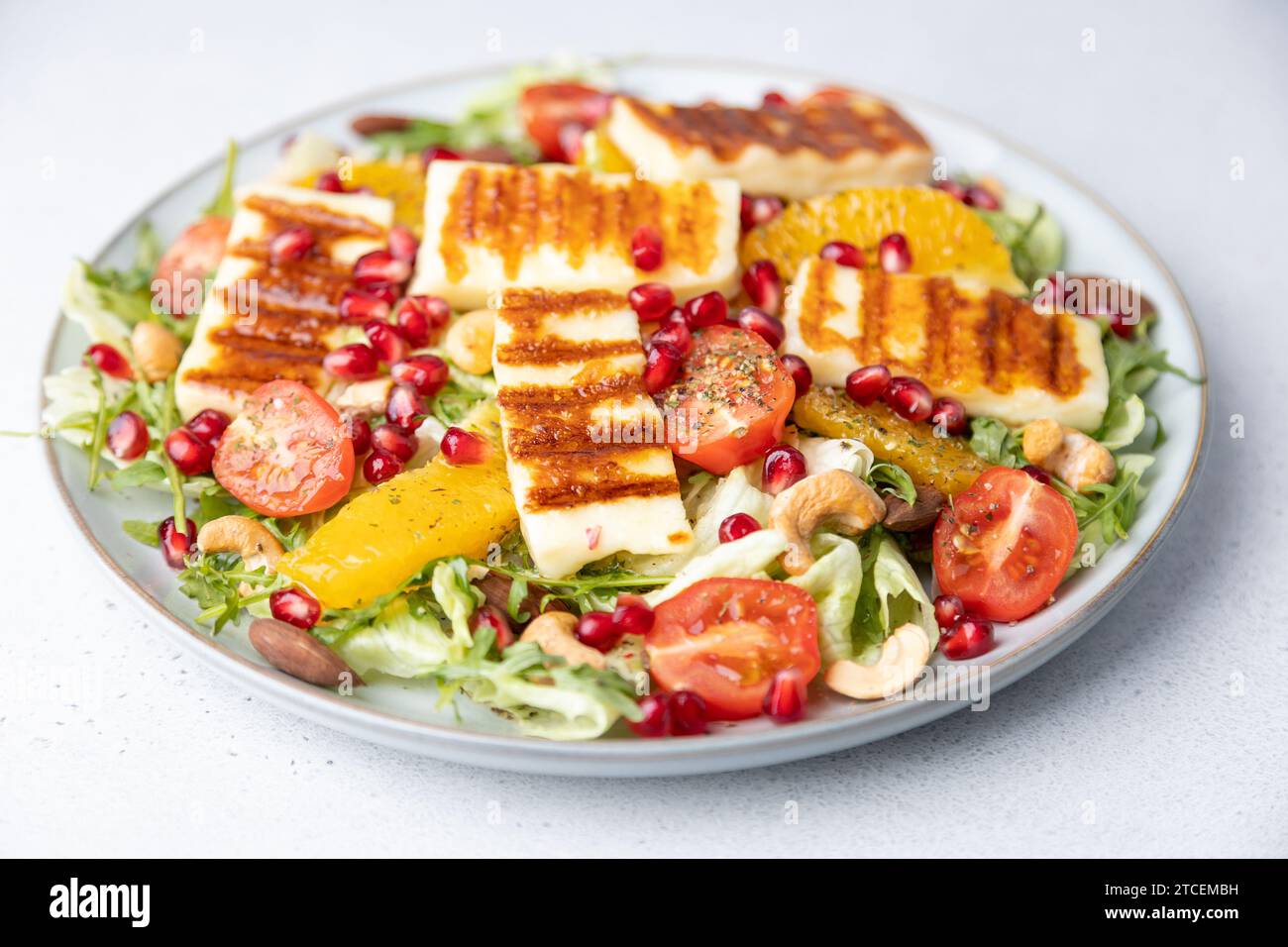 Insalata calda con formaggio halloumi fritto, noci (anacardi e mandorle), pomodori ciliegini, melograno, arancia e rucola. Formaggi tradizionali dell'Oriente Foto Stock