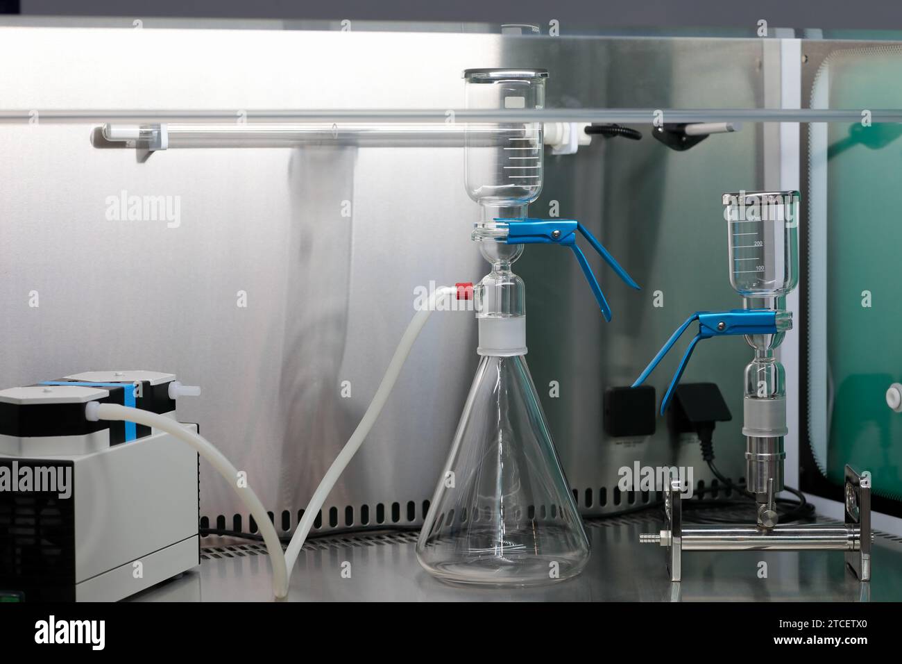 Posto di lavoro vuoto in un laboratorio di biochimica. Vetreria da laboratorio e pompa da vuoto su tavolo in acciaio inox. Messa a fuoco selettiva. Foto Stock